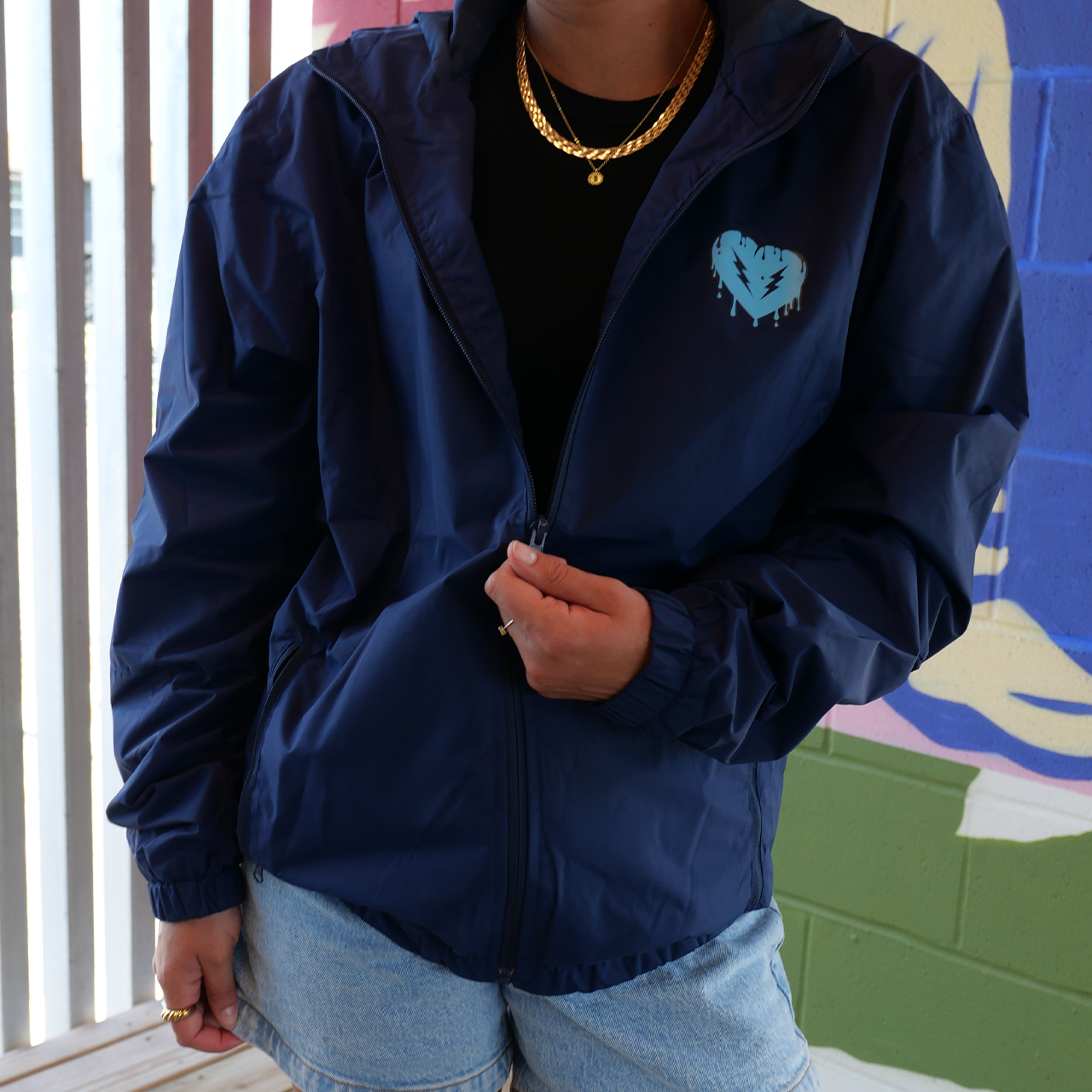 Navy blue zip-up jacket with a light blue heart logo on the chest.