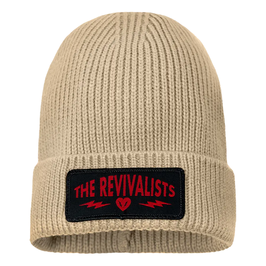 Beige knit beanie with a black patch featuring ’THE REVIVALISTS’ in red text.