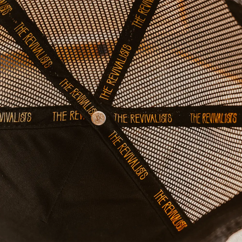 Black mesh pelican hat showing back side with gold the revivalists lettering on adjustable strap