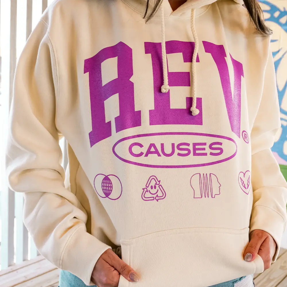 Cream-colored sweatshirt with purple ’REV CAUSES’ text and small icons printed on the front.