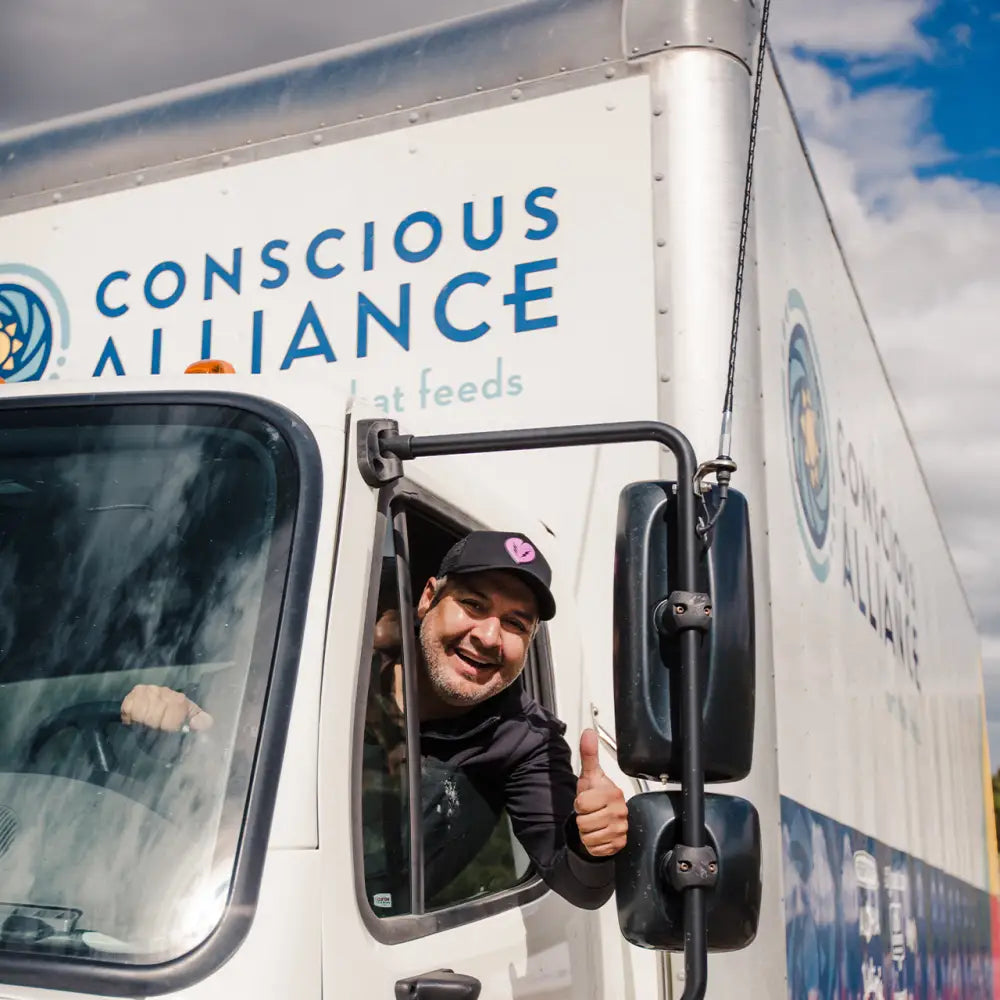 Delivery truck with ’Conscious Alliance’ branding and a person giving a thumbs-up from the driver’s window.