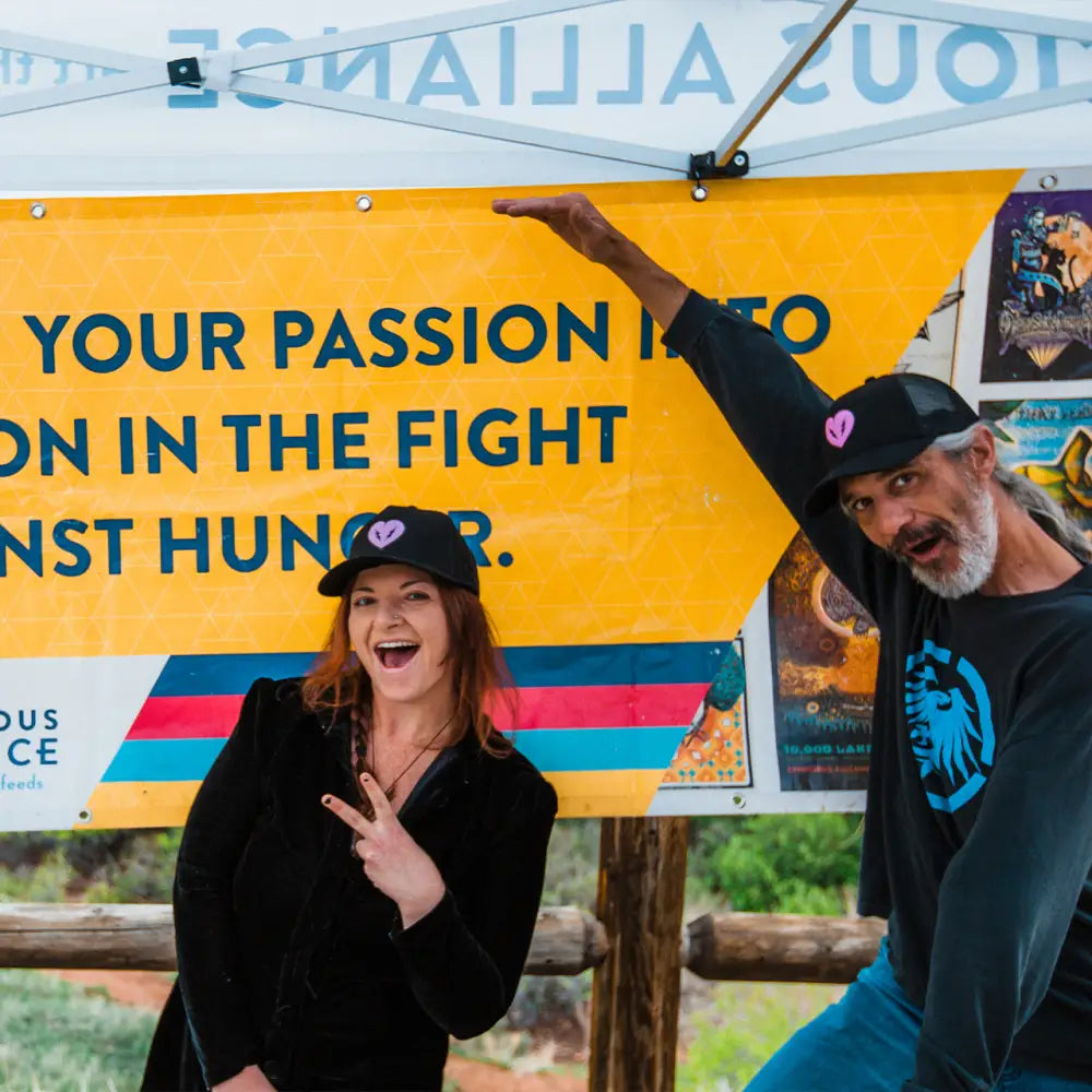 Yellow canopy or tent with text about fighting hunger, featuring two enthusiastic individuals beneath it.