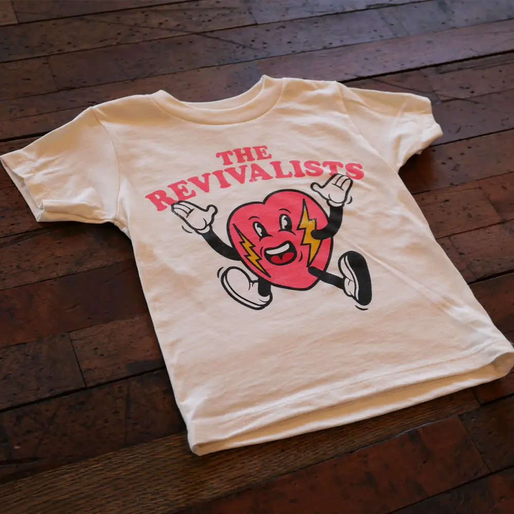 White t-shirt with a red cartoon character and ’The Revivalists’ text printed on it.