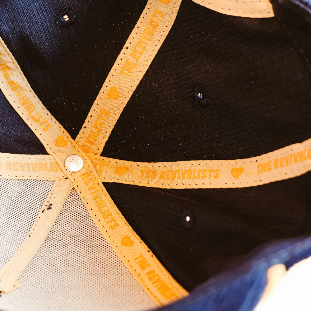 Black snake hat with orange fabric straps featuring the revivalists branding and heart motifs secured by a silver button