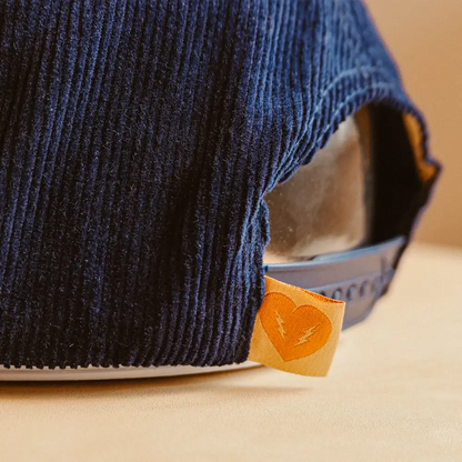 A navy blue corduroy snake hat baseball cap with an orange heart-shaped tag as a key feature
